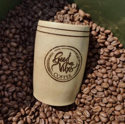 Wooden cup with 'Good Vibes Coffee' branding surrounded by coffee beans